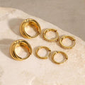 Luma Huggies non-tarnish waterproof gold hoop earrings in stainless steel displayed on neutral stone surface