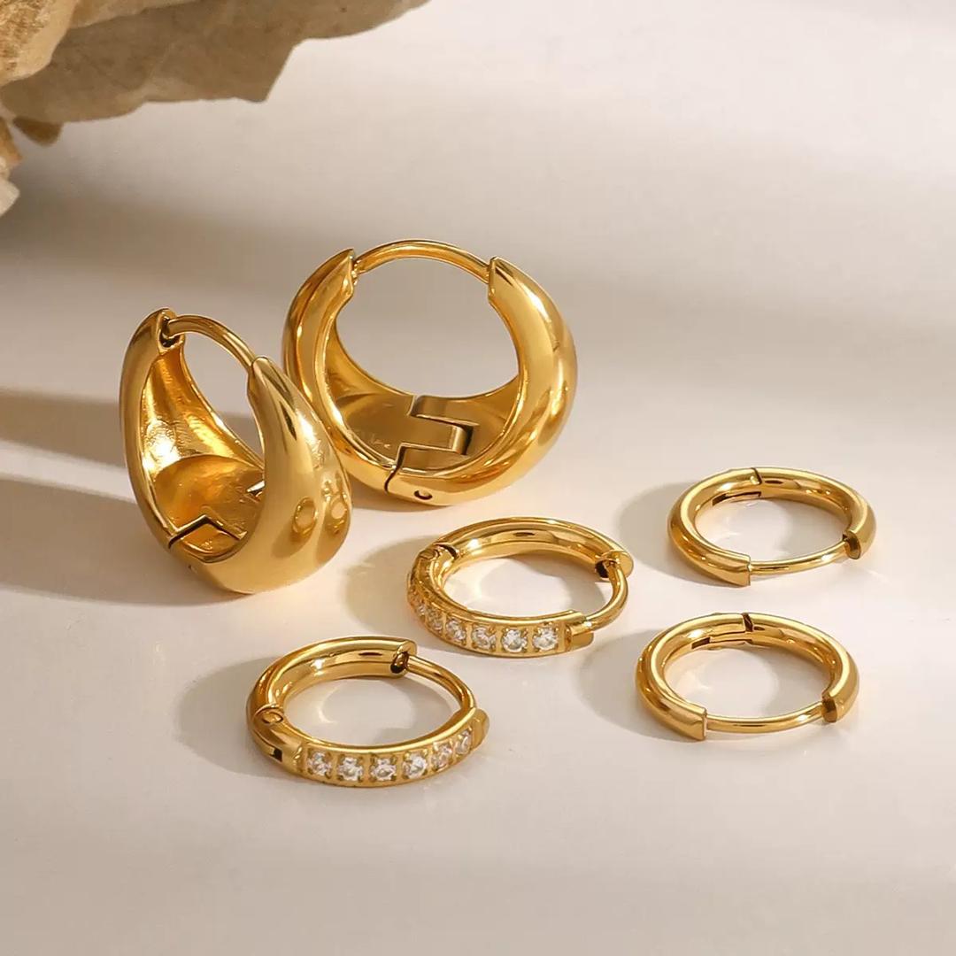 Luma Huggies non-tarnish waterproof gold hoop earrings in stainless steel displayed on neutral stone surface